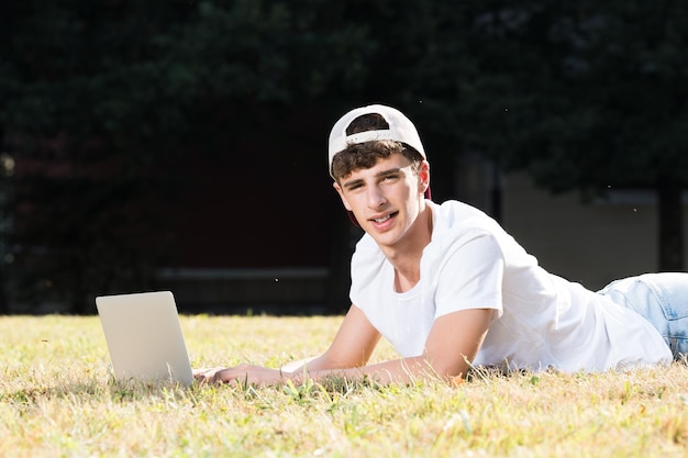 Teenager boy working on laptop and looking at camera