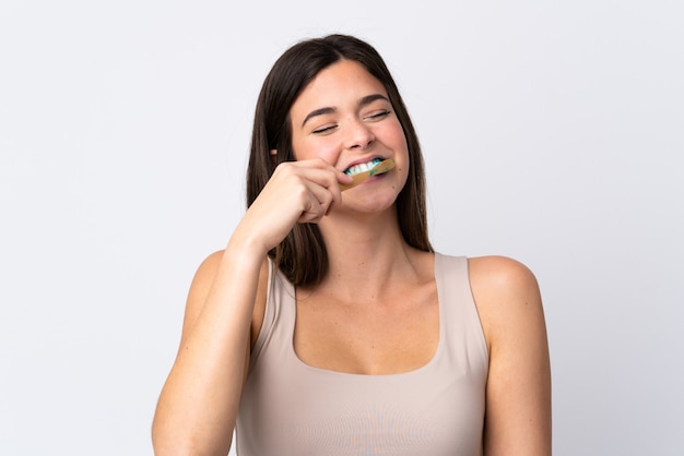 Teenager Brazilian girl brushing her teeth over isolated white wall