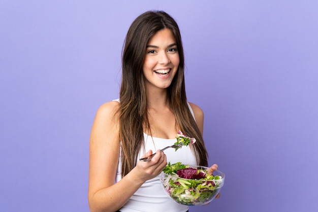 Photo teenager brazilian girl holding a salad over isolated purple background