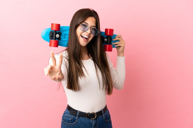 勝利のジェスチャーをしているスケートと孤立した背景上のティーンエイジャーのブラジルの女の子