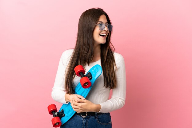 Teenager Brazilian girl over isolated background with a skate with happy expression