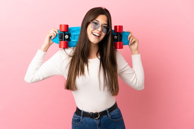 Teenager Brazilian girl isolated background with a skate with happy expression