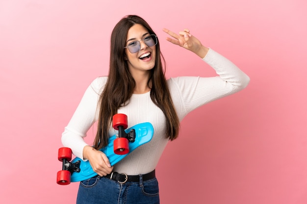 Teenager Brazilian girl isolated background with a skate with happy expression