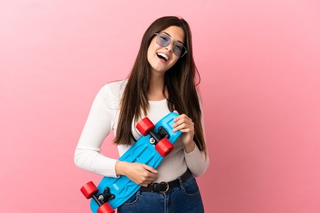 Teenager Brazilian girl over isolated background with a skate with happy expression