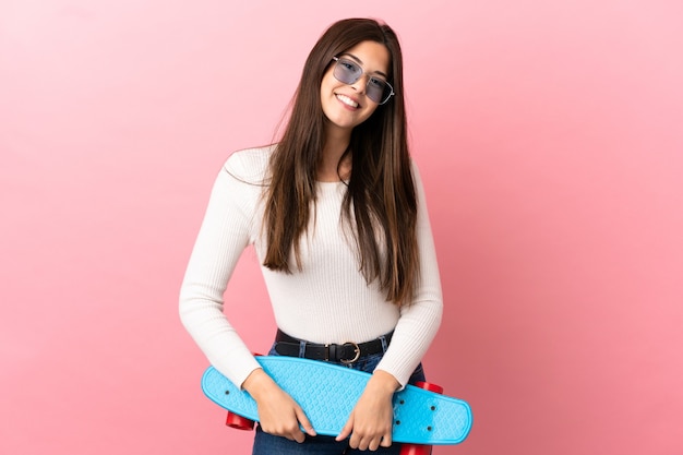 Teenager Brazilian girl over isolated wall with a skate with happy expression