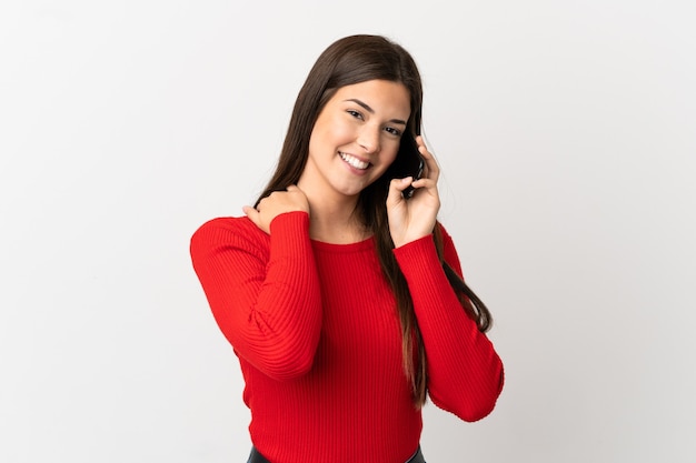 Teenager Brazilian girl using mobile phone over isolated white background laughing