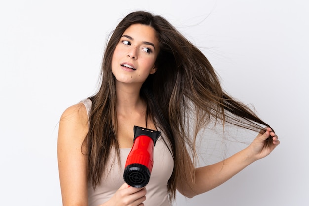 Teenager Brazilian girl with hairdryer over isolated white background