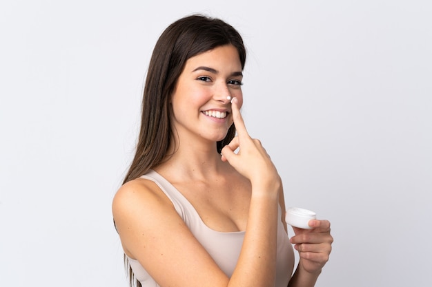 Teenager Brazilian girl with moisturizer over isolated white background