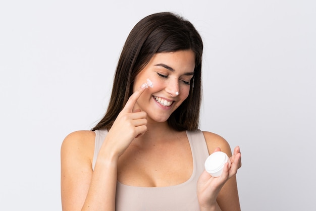 Teenager Brazilian girl with moisturizer over isolated white background