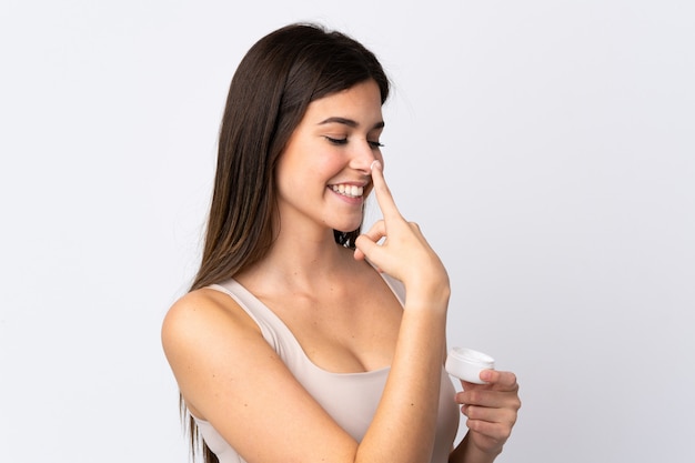 Teenager Brazilian girl with moisturizer over isolated white wall