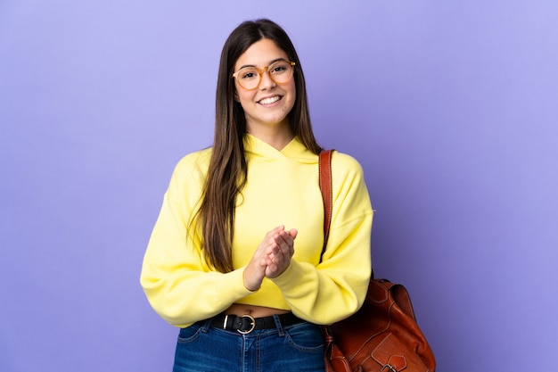 Teenager Brazilian student girl over isolated purple background applauding