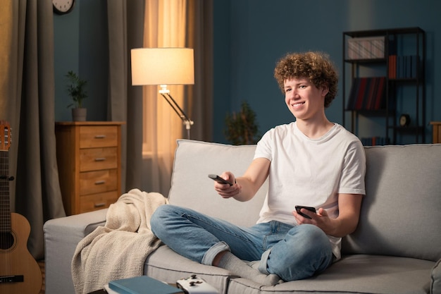 A teenager a brunette with curly hair relaxes on the living room couch in the evening