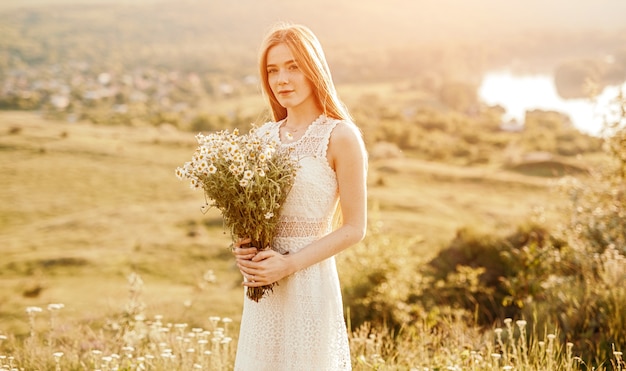 Teenager carrying bunch of fresh wild flowersin a field