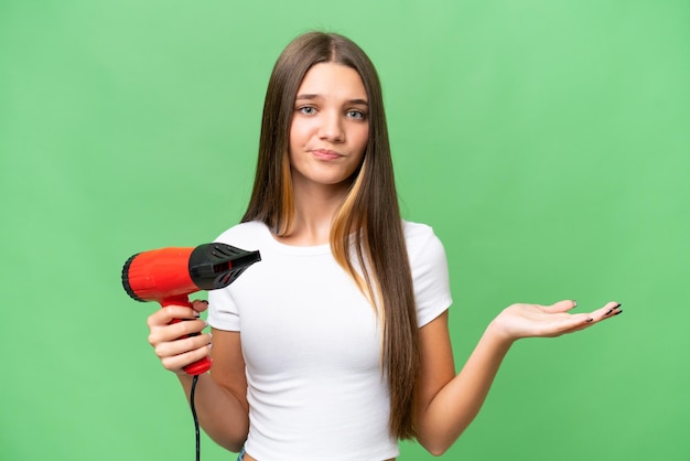 Teenager Caucasian girl holding a hairdryer over isolated background making doubts gesture while lifting the shoulders