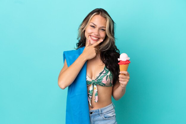 Teenager caucasian girl holding ice cream and towel isolated on blue background happy and smiling