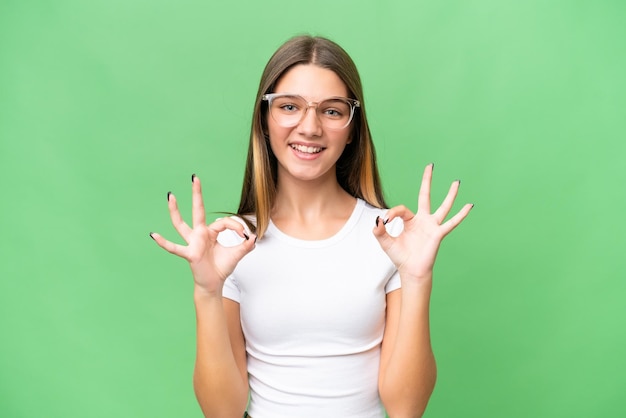 Photo teenager caucasian girl over isolated background showing ok sign with two hands