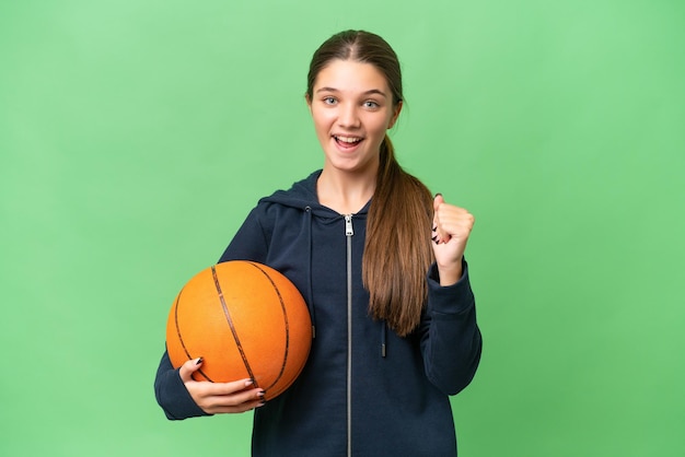 Teenager caucasian girl playing basketball over isolated background celebrating a victory in winner position