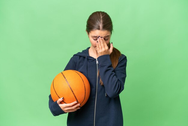 Кавказская девушка-подросток играет в баскетбол на изолированном фоне с усталым и больным выражением лица