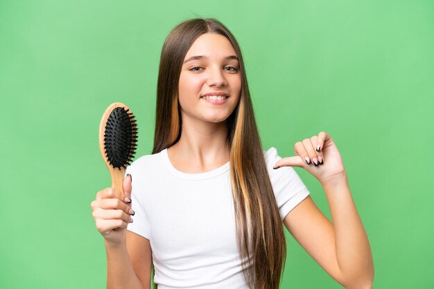 Кавказская девушка-подросток с расческой для волос на изолированном фоне гордая и самодовольная