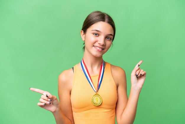 Teenager caucasian girl with medals over isolated background pointing finger to the laterals and happy