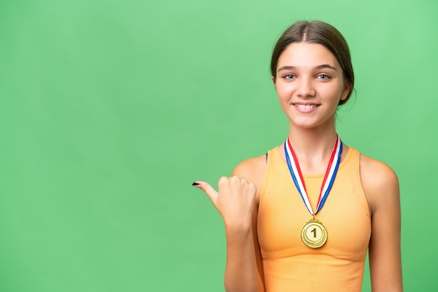 Photo teenager caucasian girl with medals over isolated background pointing to the side to present a product