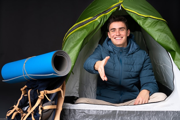Фото Подросток кавказских человек в палатке зеленый кемпинг, изолированных на черном фоне рукопожатие для закрытия хорошей сделки