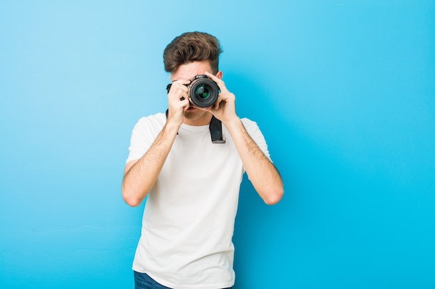 Teenager caucasian man taking photos with a reflex camera