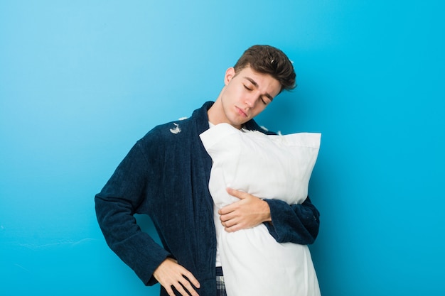 Photo teenager caucasian tired man holding a pillow