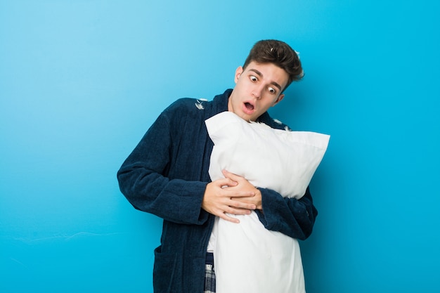 Teenager caucasian tired man holding a pillow