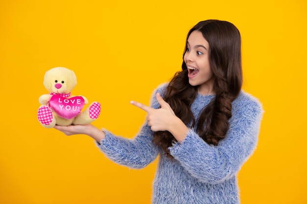 Teenager child girl in holding plush toy isolated on yellow\
background happy childhood happy teenager positive and smiling\
emotions of teen girl