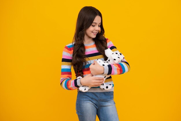 Teenager child girl in holding plush toy isolated on yellow\
background happy childhood happy teenager positive and smiling\
emotions of teen girl