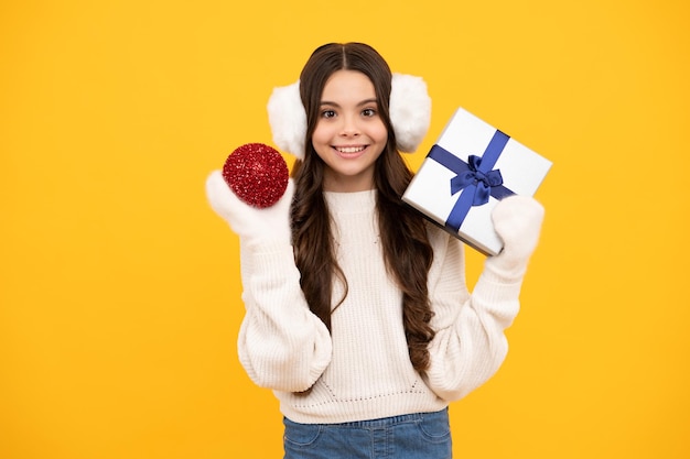 노란색 스튜디오 배경에 격리된 선물 상자를 들고 있는 10대 소녀 현재 인사말 및 선물 개념 새해 또는 크리스마스 휴가 개념