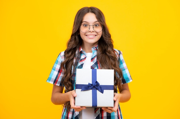 Adolescente bambino azienda confezione regalo su sfondo giallo isolato regalo per bambini compleanno natale o capodanno presente scatola