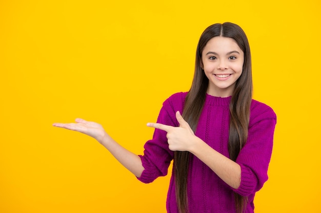 Teenager child pointing to the side with a finger to present a product or idea Teen girl in casual outfit pointing empty space