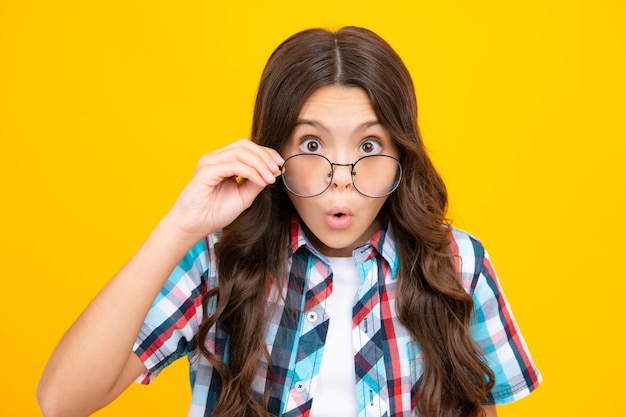 Teenager child wearing glasses on yellow studio background cute girl in eyeglasses shocked surprised teenager girl