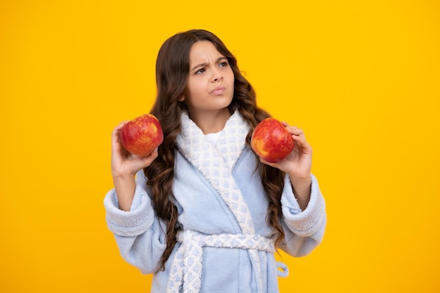 Teenager child with apple on yellow isolated background apples are good for children Thinking pensive clever teenager girl