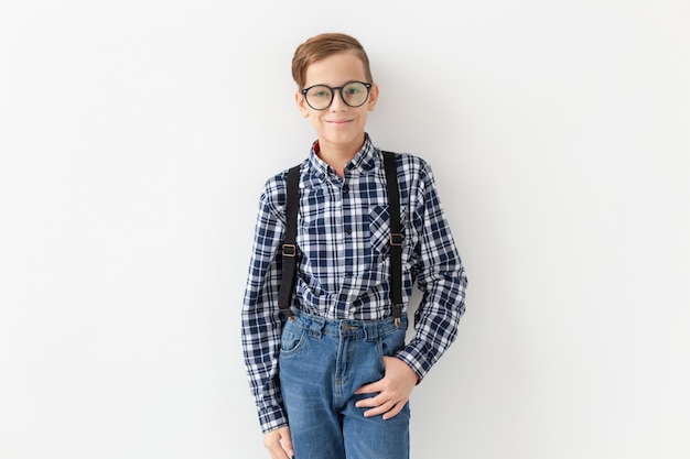 Teenager, children and fashion concept - kid dressed in plaid shirt posing over white wall