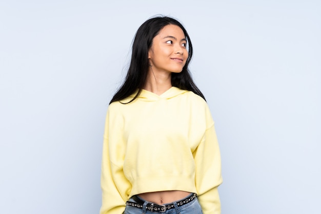 Teenager Chinese woman isolated on blue