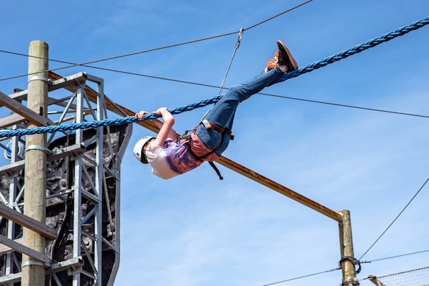 Teenager climbing on track with obstacles in adventure park