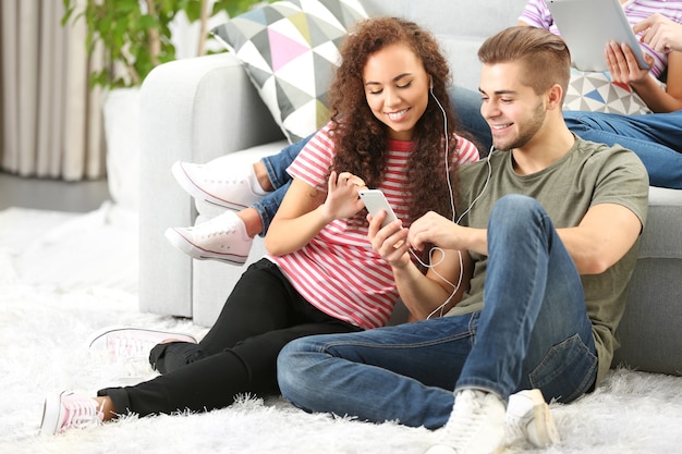 Teenager couple listening to music with mobile phone in living room