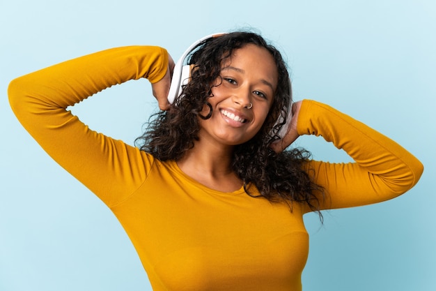 Teenager cuban girl isolated on blue background listening music