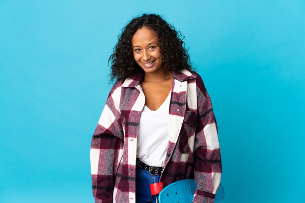 Teenager cuban girl isolated on blue background with a skate