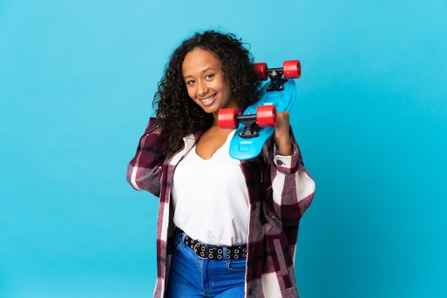 Teenager cuban girl isolated on blue background with a skate