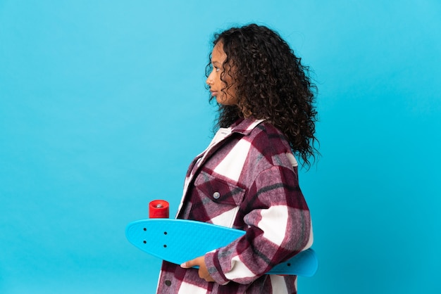 Teenager cuban girl isolated on blue  with a skate