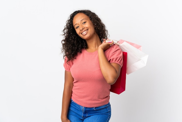 Teenager cuban girl isolated on white background holding shopping bags and smiling