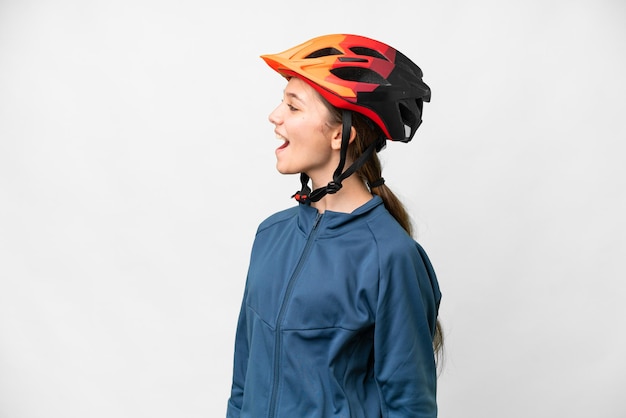 Teenager cyclist girl over isolated white background laughing in lateral position