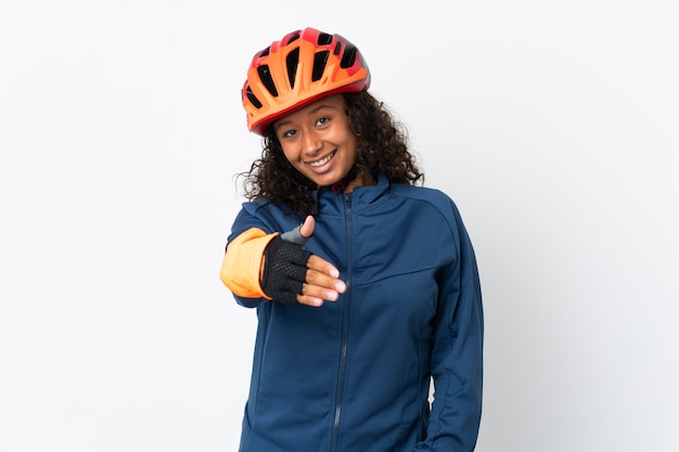 Teenager cyclist woman isolated on white background shaking hands for closing a good deal