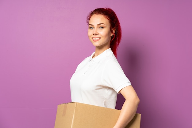 Teenager delivery girl isolated on purple background with arms crossed and looking forward