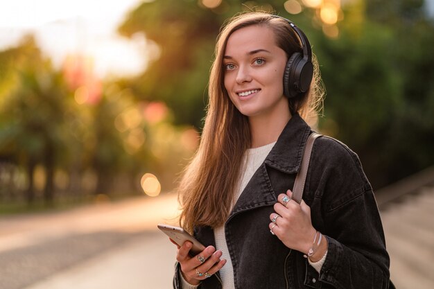 Teenager enjoys and listens to music in black wireless headphones while walking around the city