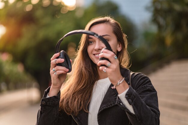 L'adolescente si diverte e ascolta la musica in cuffia wireless nera mentre cammina per la città